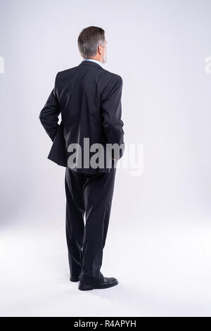 Businessman standing back to camera les mains sur les hanches sur fond blanc. Banque D'Images