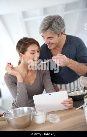 L'homme ayant sa femme préparation gâteau dégustation Banque D'Images