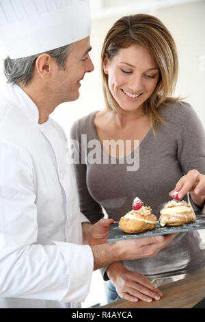 Pâtissier ayant femme pâtisseries dégustation Banque D'Images