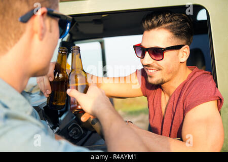 Portrait de deux amis le grillage avec des bouteilles de bière en voiture. Banque D'Images