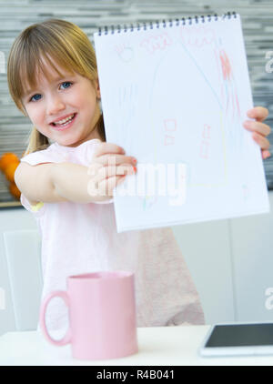 Dessin de l'enfant avec des crayons, assis à table dans la cuisine à la maison Banque D'Images