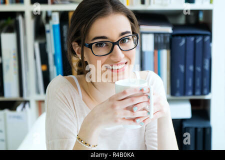 Jeune femme ayant le café dans son bureau Banque D'Images