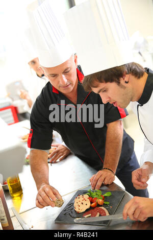 Aide cuisinier dans la restauration des étudiants de préparer le plat de foie gras Banque D'Images