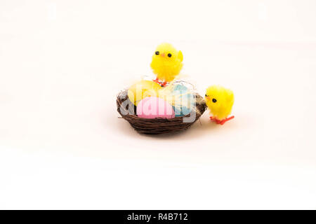 Easter fluffy toy chicks on nest avec trois oeufs contre fond blanc. Banque D'Images
