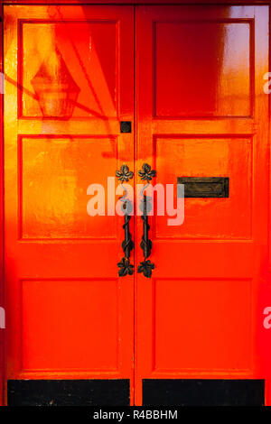 Soleil du matin en projetant une ombre de lampe sur une porte rouge vif à Dublin, Irlande Banque D'Images