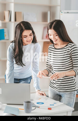 Plan d'affaires. Deux femmes d'affaires prometteuses de faire des photos tout en travaillant sur leur plan d'affaires Banque D'Images