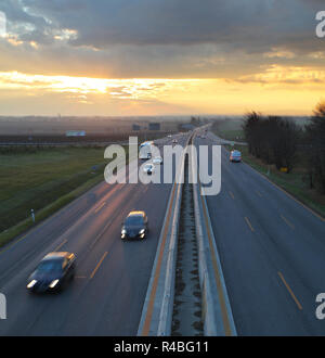 La circulation automobile contre le fond coucher de soleil. Banque D'Images
