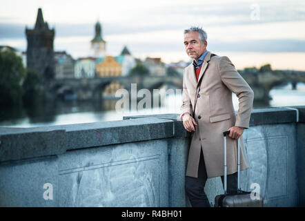 Mature businessman with suitcase debout sur un pont dans la ville de Prague. Banque D'Images