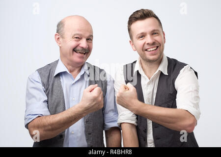 Deux copains heureux de porter veste et chemise en souriant et montrant les if Banque D'Images
