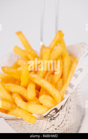 Panier de frites fraîchement faite sur fond studio blanc Banque D'Images