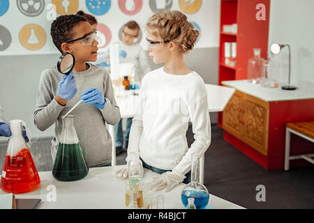 Jetez un coup d'oeil. Cheerful African boy portant des lunettes de sécurité lors de l'expérience chimique Banque D'Images