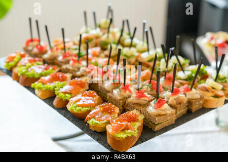 Crostini avec garnitures différentes sur fond de bois. De délicieux hors-d'œuvre. Vue de face. Hors-d'œuvre gastronomique : caviar, venaison, thon et saumon Banque D'Images