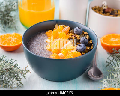 Chia pudding avec mandarine et thé matcha dans un bol de granola sur fond de bois turquoise pastel. Petit-déjeuner à base de plantes Banque D'Images