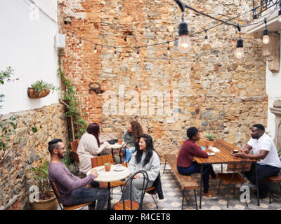 Diverses personnes parlant ensemble autour d'un café dans un café courtyard Banque D'Images