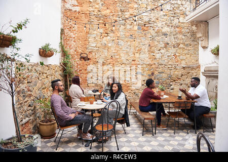 Diverses personnes de conversations au café dans un café branché de cour intérieure Banque D'Images