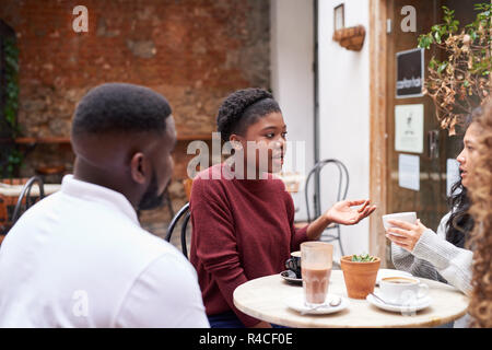 Divers amis parler autour d'un verre dans un café branché de cour intérieure Banque D'Images