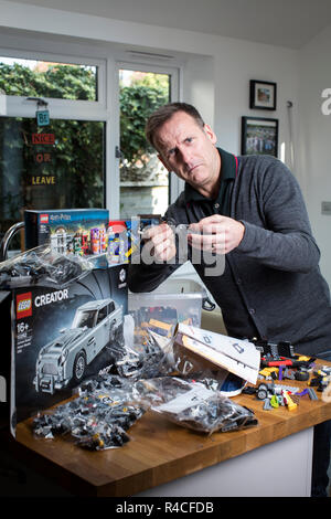 Homme d'âge moyen à la maison lego construction en Angleterre, comme les adultes, sont l'admission à la dépendance à l'édifice en brique de phénomène, Royaume-Uni. Banque D'Images