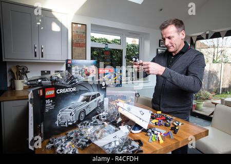 Homme d'âge moyen à la maison lego construction en Angleterre, comme les adultes, sont l'admission à la dépendance à l'édifice en brique de phénomène, Royaume-Uni. Banque D'Images