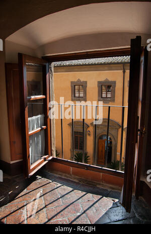 Vue depuis une fenêtre du château d'eau : la lumière sur un sol en pierre à travers une fenêtre donnant sur la cour d'un château en Toscane. Banque D'Images
