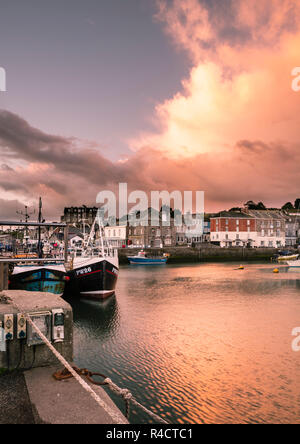 La lumière tôt le matin plus de Padstow Harbour, North Cornwall. Ciel dramatique reflète dans l'eau avec des bateaux de pêche dans l'avant-plan Banque D'Images