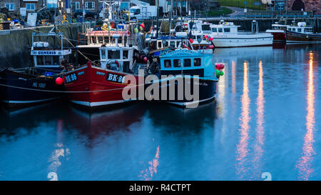 Port de Seahouses au crépuscule avec les bateaux de pêche et de lumières qui se reflète sur l'eau Banque D'Images