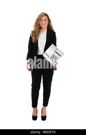 Businesswoman standing dans le studio avec ordinateur et caisse enregistreuse sous ses bras, elle porte un costume noir et chemise blanche Banque D'Images