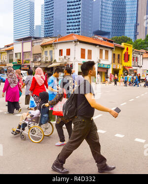 Singapour - 17 févr. 2017 : Les personnes qui traversent la route dans le quartier chinois de Singapour. Les gratte-ciel modernes de Singapour au centre-ville sur un arrière-plan. Banque D'Images