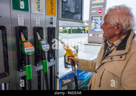 Un homme âgé de la sélection de la pompe à carburant diesel injecteur et regarder cher prix au distributeur de carburant de station d'essence pour faire le plein de son véhicule en Belgique, Europe Banque D'Images