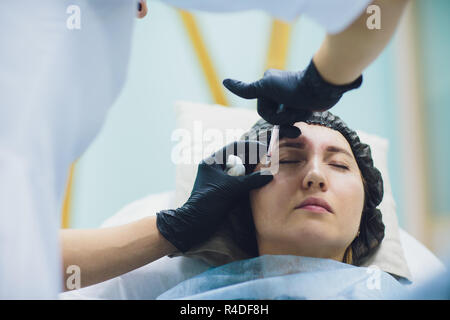 Cosmetologist médecin à établir la beauté du visage injections pour sa femme client. Beau visage de femme et ses mains avec de cosmetologist seringue. Rajeunissement et hydratation. Concept de cosmétologie en clinique. Banque D'Images