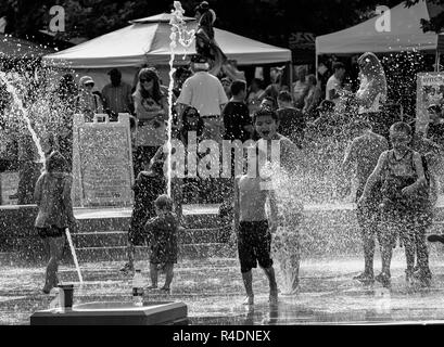 Un petit garçon halète sous le choc à l'eau froide, comme un autre rit de son malaise, dans le dispositif de l'eau 'plashville» à Asheville, NC, USA Banque D'Images