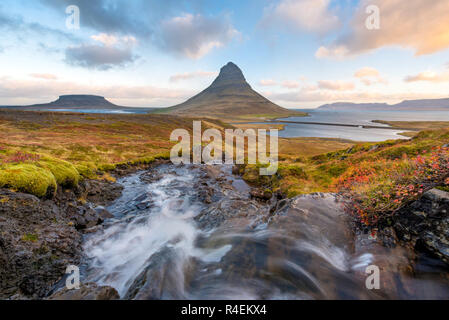 Haut de la sunrise incroyable chute d'Kirkjufellsfoss avec Kirkjufell mountain en arrière-plan sur la côte nord de l'Islande, péninsule de Snæfellsnes pris un long blanc vitesse d'obturation. Banque D'Images