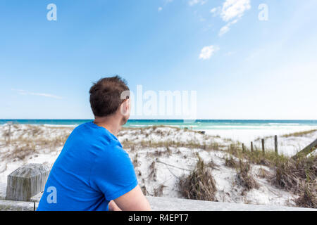 Destin, USA Miramar Beach ville village ville jour en Floride Golfe du Mexique, de l'eau de l'océan en gros plan homme chemise bleue leaning on woode Banque D'Images