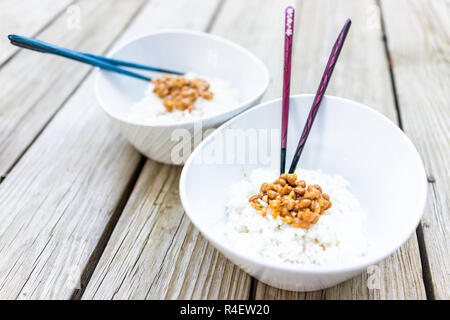 Libre de paire de baguettes asiatique sur le natto japonais repas plat de soja fermenté, collant, texture visqueuse dans du papier blanc dans deux bols de riz cuit à la vapeur Banque D'Images