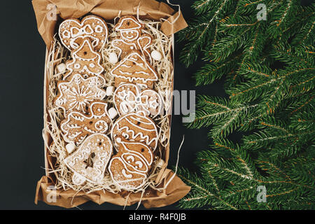 Superbe boîte cadeau avec Noël gingerbread cookies avec le glaçage et branches de sapin vert sur l'arrière-plan du tableau noir. Mise à plat. Vue d'en haut Banque D'Images