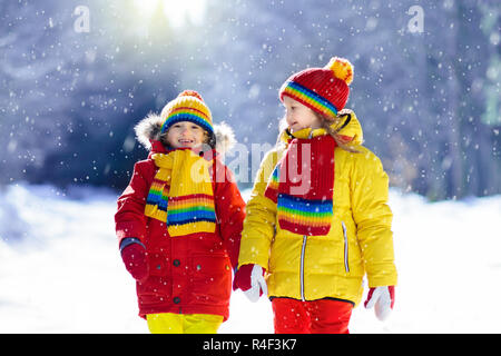 Les enfants jouent dans la neige. Les enfants jouer dehors sur le jour d'hiver enneigé. Garçon et fille attraper des flocons de neige dans la tempête. Frère et sœur throwing snow Banque D'Images