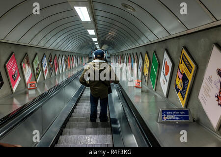 Parka homme en casque et en descendant l'ascenseur dans le métro de Londres Banque D'Images