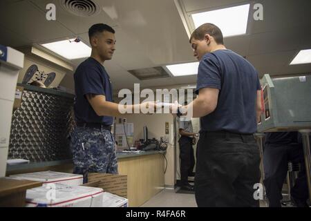 Le Golfe Arabique (oct. 25, 2016) Seaman Jose Rivera, gauche, de Bronx, N.Y., distribue des cartes de bien-être dans la bibliothèque du porte-avions USS Dwight D. Eisenhower (CVN 69) (Ike). Fil sert à bord d'Ike, spécialiste de programmes religieux aumôniers aidant à faciliter le bien-être de l'équipage et les pratiques religieuses. Ike et son Groupe aéronaval sont déployés à l'appui de l'opération inhérents à résoudre, les opérations de sécurité maritime et les efforts de coopération en matière de sécurité dans le théâtre dans la 5e flotte américaine zone d'opérations. Banque D'Images