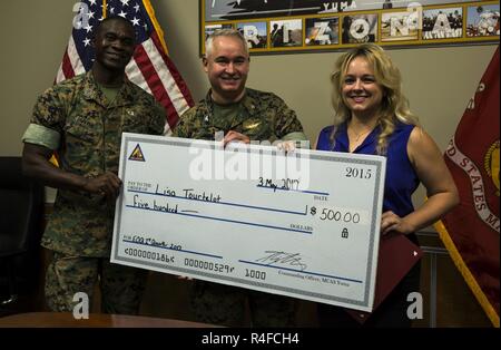 Le sergent du Corps des Marines des États-Unis. Le major Delvin Smythe (à gauche), le sergent-major de la Marine Corps Air Station Yuma (Arizona), et le Colonel Ricardo Martinez (centre), le commandant du MCAS Yuma, présent Lisa Tourtelot (à droite), l'adjoint aux affaires publiques Affaires publiques de MCAS Yuma et Caméra de combat, avec un chèque de cinq cents dollars en plus de la MCAS Yuma employé de la 2e trimestre award au quartier général de la station, le 3 mai 2017. Banque D'Images