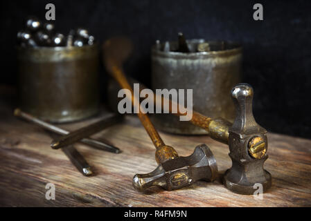 Old vintage marteaux et poinçons en acier marque sur un banc en bois rustique, d'un orfèvre sur un fond sombre, étroit, de discussion, de profondeur Banque D'Images