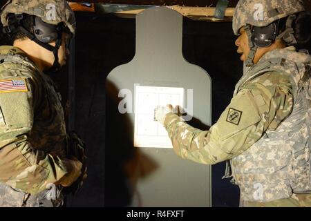 Le sergent de l'armée américaine. P. Astin Muse, affecté à la 39e Bataillon du signal, vérifie les impacts de un M4 carbin tiré par le Sgt. Jerrell D. Chevalier à la gamme de 25 mètres sur la base aérienne de Chièvres, Belgique, le 24 octobre 2016. Banque D'Images