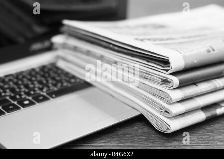 Journaux et ordinateur portable. Pile de quotidiens avec des news sur ordinateur. Avec Pages, des articles pliés et empilés sur le clavier de l'appareil électronique Banque D'Images