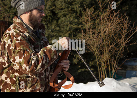 Forêt en hiver homme recharge armes pneumatiques. hunter tenue de camouflage avec carabine, pistolet pneumatique Banque D'Images