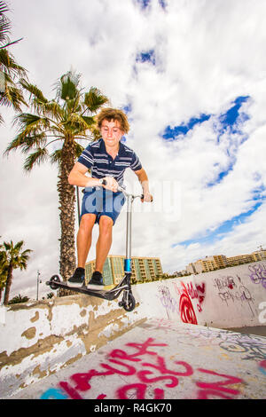 Garçon a fun riding push son scooter à la skatepark Banque D'Images