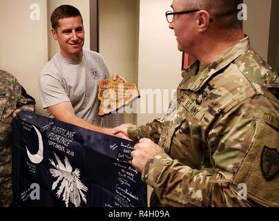Le Major de l'armée américaine Trevor Patrick, à gauche, avec l'Oregon Garde nationale, reçoit une plaque commémorative et le drapeau du lieutenant-colonel Douglas Leslie, avec la Garde nationale de Caroline du Sud, à l'Aéroport International de Myrtle Beach, le 27 septembre 2018. Leslie a remercié les membres de la Garde nationale de Pennsylvanie pour leurs efforts au cours de l'ouragan Florence mission de secours. Banque D'Images