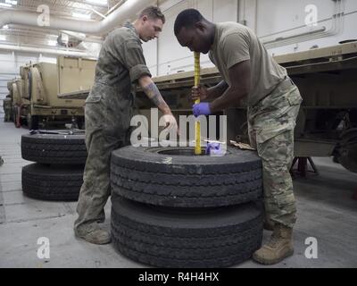 La CPS de l'armée. Bradley McAfee, originaire de Reading, Pa., affecté à la 109e compagnie de transport, 17e Bataillon de soutien au maintien en puissance de combat de l'armée américaine, l'Alaska, indique à la CPS. Leroy Porte, originaire de Sacramento, Californie, siège de roulements de roue fraîchement graissés comme processus d'autres soldats nouvelles remorques et effectuer l'entretien sur l'équipement actuel à leur unité motor pool sur Joint Base Elmendorf-Richardson, Alaska, le 28 septembre 2018. La 109TC Des soldats effectuent le transport de véhicule et matériel hebdomadaire de missions et d'USARAK vital actif dans l'Alaska, ainsi que maintenir l'état de préparation pour deploym Banque D'Images