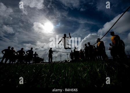 Les soldats, marins, aviateurs et marines se relaient sautant par-dessus une corde pendant le Défi de remise en forme mixte d'Okinawa, le 26 septembre 2018, à Kadena Air Base, au Japon. Corde à sauter le défi exige de tous les 48 élèves à saute sur la corde s'il est en mouvement. Si la corde a touché un étudiant alors qu'ils sautaient dessus, ou si la corde est arrêté, les élèves devraient commencer plus d'encore. Banque D'Images