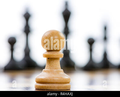 Le pion blanc contre une supériorité des pièces d'échecs noir Banque D'Images