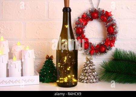 Garland dans la bouteille. Bouteille de champagne vide avec guirlande à l'intérieur sur le tableau blanc. Décor lumineux pour Noël. Bricolage à la main, de leurs propres mains. Banque D'Images