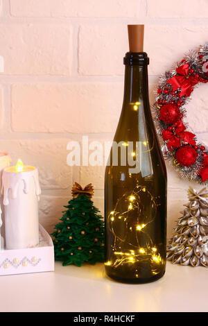 Garland dans la bouteille. Bouteille de champagne vide avec guirlande à l'intérieur sur le tableau blanc. Décor lumineux pour Noël. Bricolage à la main, de leurs propres mains. Banque D'Images