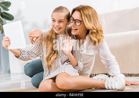 Focus sélectif de l'heureux grand-mère et sa petite-fille en agitant la main et avoir appel vidéo avec digital tablet Banque D'Images